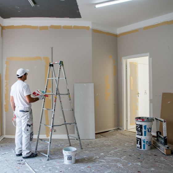 "Transformación creativa en un estudio iluminado, donde un pintor mezcla colores vibrantes, reflejando la maestría de PINTURAS Y APLICACIONES C&S en proyectos de interior y exterior."
